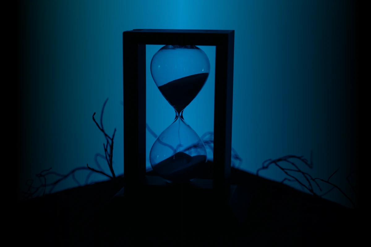 A black Silhouette of an hourglass on a blue background